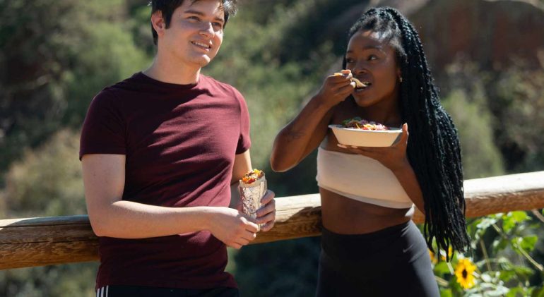 Young couple eating QDOBA on hike